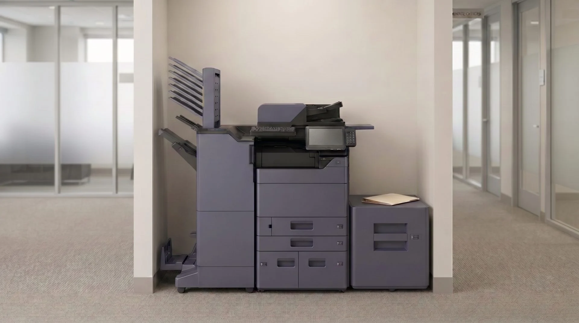 A shared printer alcove off a professional office corridor, with a closed folder on a side table beside the machine.