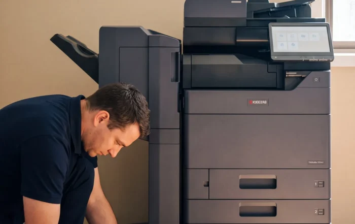 Global Document Solutions technician fitting a toner cartridge to a leased Kyocera TASKalfa 2554ci in a customer office