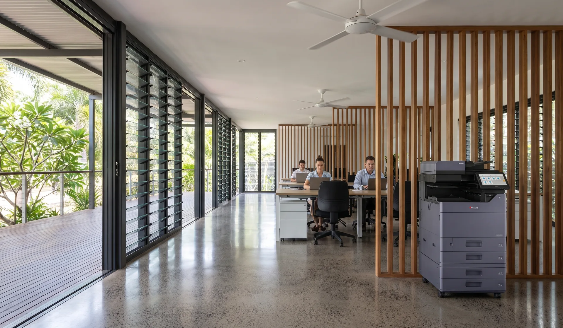 Kyocera multifunction printer in an open plan Darwin office with louvred windows, ceiling fans, timber battens and a tropical garden deck