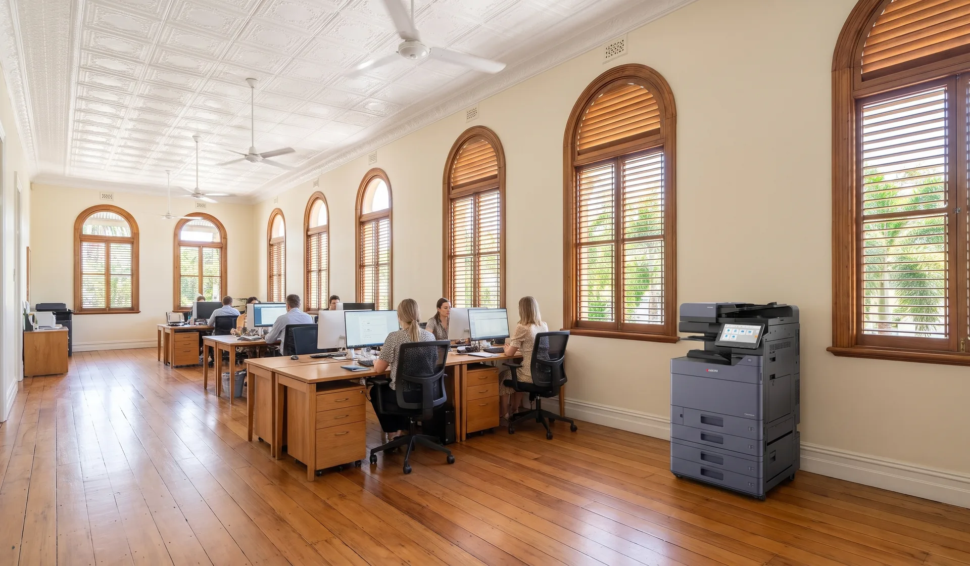 Kyocera multifunction printer in an open plan Townsville office inside a restored heritage building with arched windows and ceiling fans