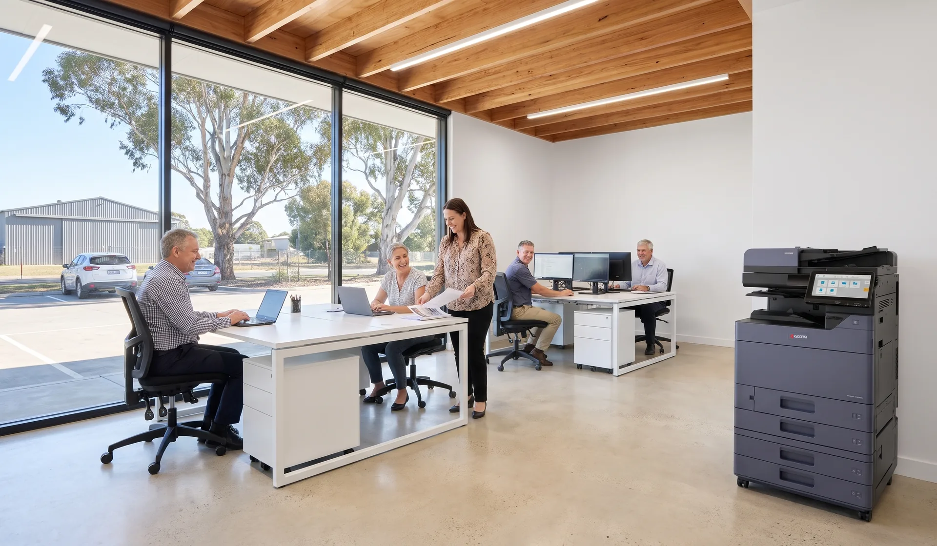 Smiling team in a Wodonga business park office working beside a Kyocera multifunction printer