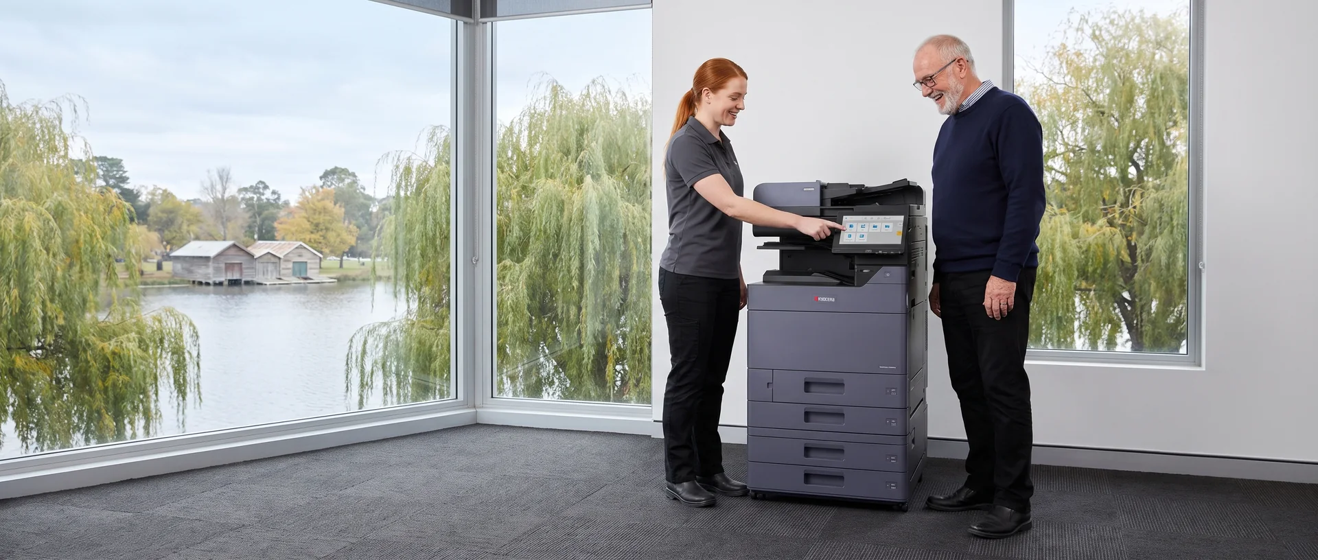 Smiling technician showing an older office manager the touch screen of a leased Kyocera copier beside Lake Wendouree in Ballarat