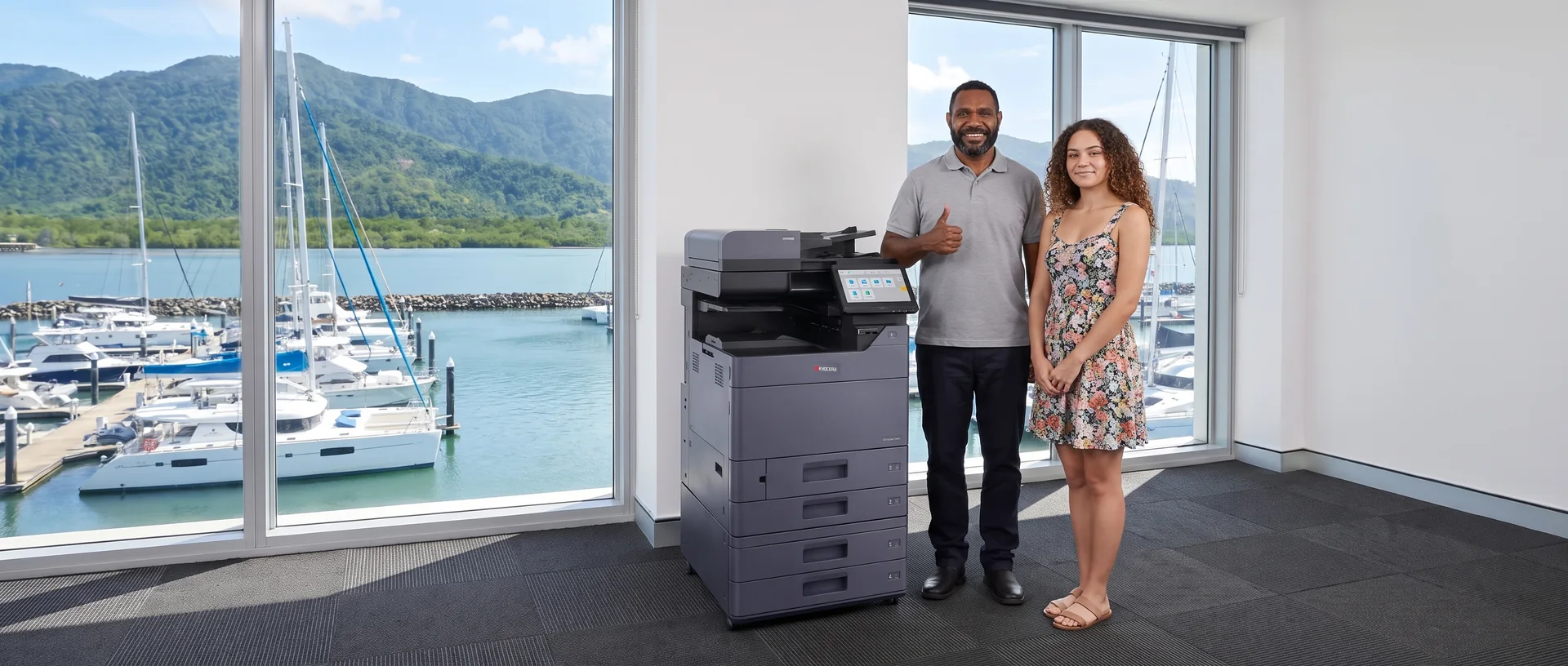 Technician giving a thumbs up beside a leased Kyocera printer with a staff member in a Cairns office overlooking the marina