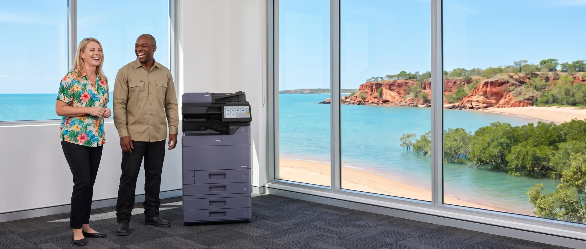 Technician laughing with a staff member beside a leased Kyocera printer in a Darwin office overlooking red cliffs and the sea